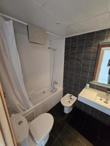 Un baño con inodoro, bañera y lavabo. en Piscina y Pádel al lado del Mar, en Torredembarra