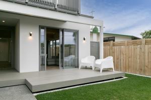 two white chairs sitting on a porch of a house at Taradale Gem in Napier
