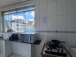 a kitchen with a stove and a window at Kitnet no centro de Betim in Betim