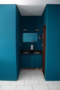 a blue bathroom with a sink and a mirror at Kitnet no centro de Betim in Betim
