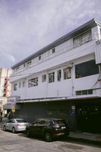 two cars parked in front of a white building at Kitnet no centro de Betim in Betim