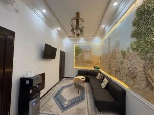 a living room with a couch and a painting on the wall at SumayShakh Guest House in Bukhara