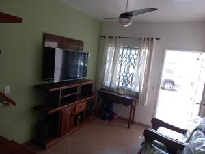 a living room with a flat screen tv on a wooden entertainment center at Ótima Casa em Muriqui in Mangaratiba +4 photos