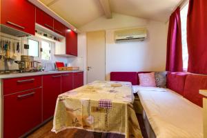 a small kitchen with red cabinets and a table at Apartments by the sea Cove Kurila, Losinj - 24571 in Mali Lošinj +9 photos