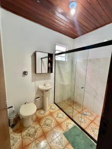 a bathroom with a toilet and a glass shower at Casa em Condomínio no Centro de Ponta Porã in Ponta Porã +6 photos