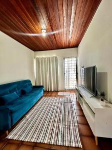 a living room with a blue couch and a television at Casa em Condomínio no Centro de Ponta Porã in Ponta Porã