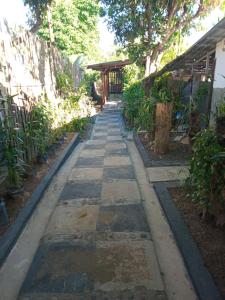 a stone walkway in a garden with a building at Dimas Cottage in Senaru