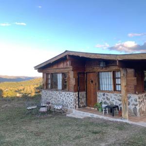 a log cabin with a table and chairs in front of it at La Chuncana in La Falda
