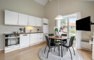 a kitchen with white cabinets and a table and chairs at 2 Bedroom Awesome Home In Gudhjem in Gudhjem