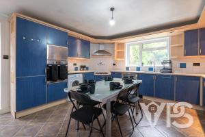 a kitchen with blue cabinets and a table and chairs at Contractors Family Near Hospital in Leicester