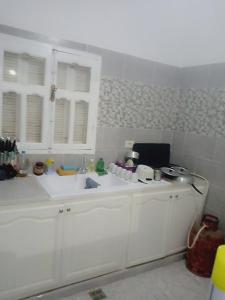eine weiße Küche mit einem Waschbecken und einer Arbeitsplatte in der Unterkunft Dar MORTADA TATAOUINE in Tataouine