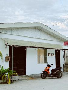 a scooter parked in front of a white building at Fika Siargao - Cozy Island Home in General Luna in General Luna