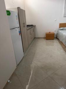 a kitchen with a white refrigerator and a bedroom at Ap Emanuel in Praia