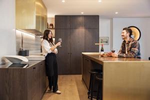 mężczyzna i kobieta stojący w kuchni z kieliszkiem wina w obiekcie The Bunkers Penthouse-1 Bed w mieście Queenstown
