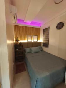 a small bedroom with a bed with purple lighting at Almond Drive Talisay in Tangke +14 photos