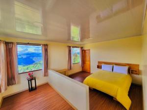 a bedroom with a yellow bed and two windows at Inti Amanta Lodge in Sigchos