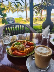 a plate of food on a table with a cup of coffee at Ramada Suites By Wyndham Seafront Coral Coast in Korotogo