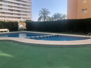 a large swimming pool with a green floor and a building at Ático dúplex en Playa Fossa Calpe in Calpe