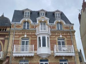 duży ceglany budynek z białym balkonem w obiekcie Appartement en front de mer à Villers-sur-Mer face au Casino, 2P tout équipé avec parking privatif - FR-1-712-14 w mieście Villers-sur-Mer
