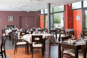 una sala da pranzo con tavoli, sedie e finestre di Logis Hôtel Terre de Loire a Belleville-sur-Loire
