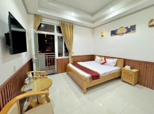 a bedroom with a bed and a table and a window at Khách Sạn Phương Khuê in Ấp Bình Hưng