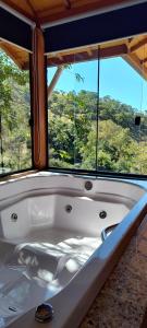 a white bath tub in front of a window at pousada caminho do escorrega in Visconde De Maua +116 photos