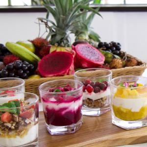 a table with four glasses of desserts and a basket of fruit at Nature's Immersion Room at Anwa Bali Boutique Resort in Canggu