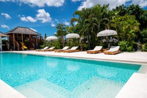 a pool at a resort with lounge chairs and umbrellas at Nature's Immersion Room at Anwa Bali Boutique Resort in Canggu