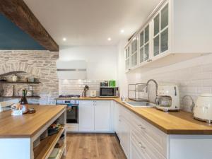 a kitchen with white cabinets and a brick wall at Maison rénovée au bord de l'Ognon avec grand jardin et plage privée - FR-1-583-395 in Cenans