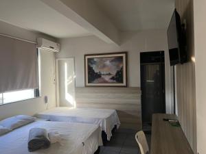 a hotel room with two beds and a table at Kris Hotel in Petrolina
