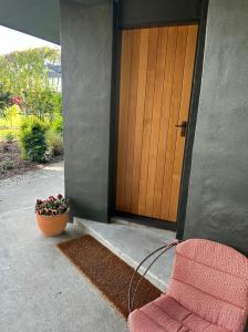een deur van een huis met een bloempot en een slang bij Puketapu Orchard Retreat in Napier