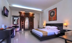 a bedroom with a large bed with a clock on the wall at Satriya Cottages in Kuta