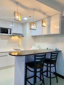 eine Küche mit zwei schwarzen Stühlen an der Theke in der Unterkunft Bright & Cozy High-Rise Condo in Pulong Cacawate