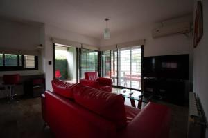 a living room with red couches and windows at LA CASITA in Roldán
