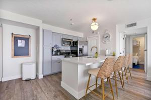 una cocina con armarios blancos y un bar con taburetes en Newly Renovated San Luis Resort luxury condo, en Galveston