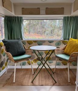 une table et des chaises dans une pièce avec une fenêtre dans l'établissement Castlemaine Gardens Vintage 60's Caravan, à Castlemaine 1 autre photo