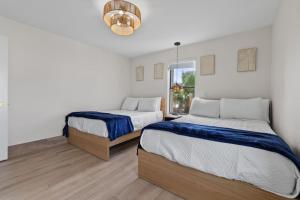 a bedroom with two beds and a chandelier at Saida I Zen by the Sea in South Padre Island +37 photos