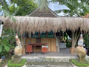 a small building with a table and a straw roof at Jatiluwih Guava Eco Living managed by Manara in Jatiluwih