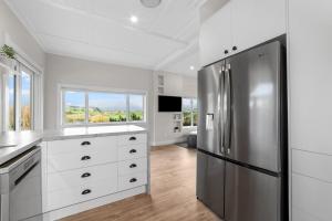 a kitchen with white cabinets and a stainless steel refrigerator at Karapiro Cottage in Karapiro