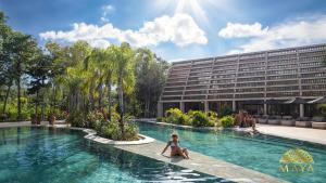 une femme assise dans une piscine devant un bâtiment dans l'établissement Peregrina Tulum 302B 1-Bedroom Luxury Condo, à Tulum