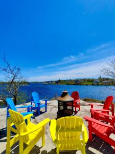 a group of colorful chairs and a fire pit on a beach at 181 Oceanside Inn in Peggy's Cove