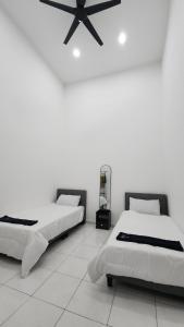 two beds in a room with a ceiling fan at Stay Put by Liza in Jasin +5 photos