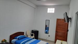 a bedroom with a bed and a tv and a door at Habitación Triple in Iquitos