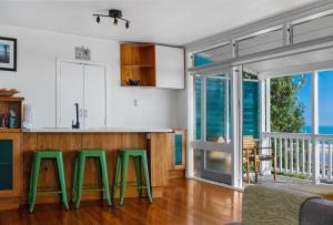 a kitchen with green stools in front of a counter at Te Hu - Ahipara Beachfront Bach in Ahipara +22 photos