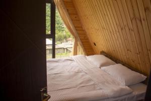 een bed in een houten kamer met een raam bij A-frame Wonder in Mestia