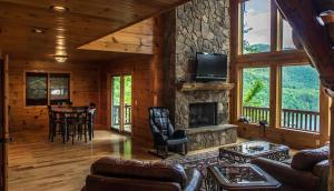 a living room with a stone fireplace in a log cabin at Majestic Manor - Peaceful Modern Cabin Retreat Near Watauga Lake in Butler