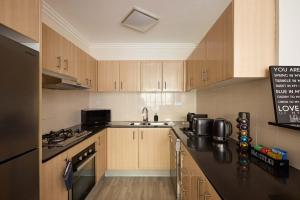 Una cocina con gabinetes de madera y una encimera negra. en Free Parking on Bunn, 5 mins to The Star & Darling, en Sídney