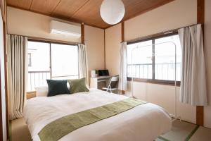 ein Schlafzimmer mit einem großen Bett und zwei Fenstern in der Unterkunft Kaze Box in Kasaoka