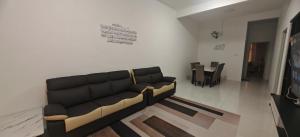 a living room with a black couch and a table at ZARI Homestay Kamunting in Gua Sai