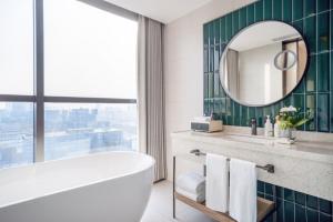 a bathroom with a tub and a mirror and a sink at EVEN Hotel Shanghai Jinqiao by IHG in Shanghai